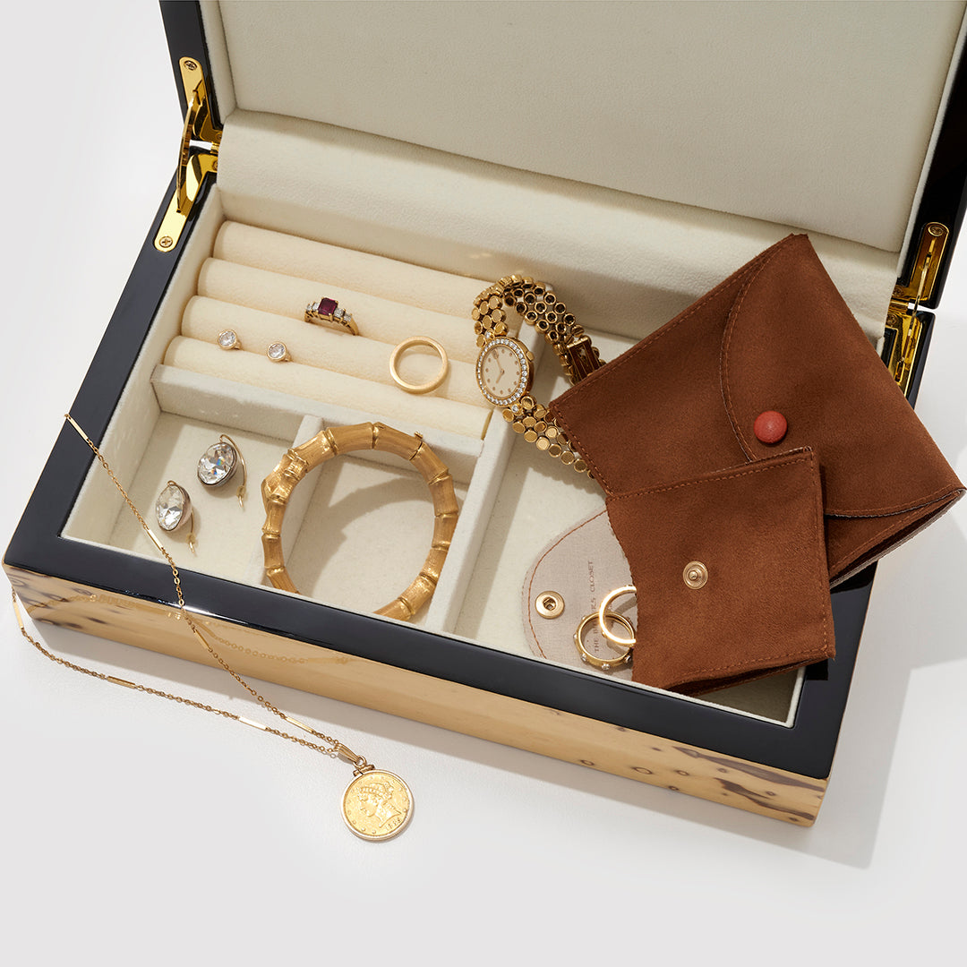 A Jewelry Box With Some Jewelry Inside And A Luxury Brown Jewelry Pouch On Top Of It