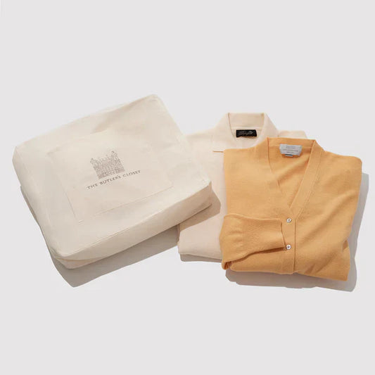 Folded sweaters and shirt beside a garment storage bag for moth prevention