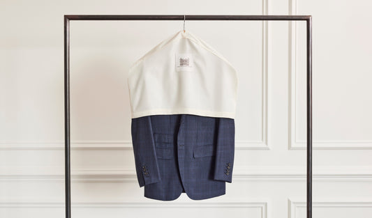 Navy Suit Jacket Hanging in White Suit Cover on Clothing Rack