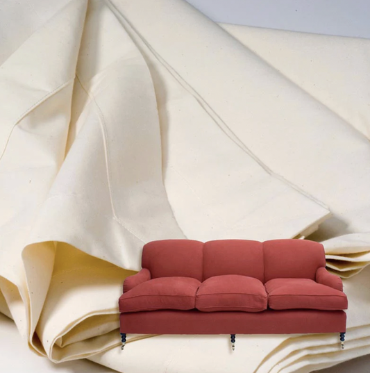 Red sofa placed in front of folded cream fabric, suggesting protective dust cover material