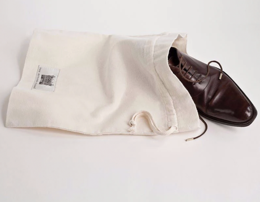 Brown leather dress shoe partially stored in a breathable cotton drawstring bag for compact closet organization