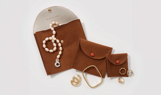 Brown leather travel jewelry cases with pearls, rings, and bracelets