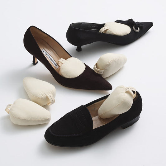 Cream-colored cotton shoe shapers placed inside and beside black dress shoes