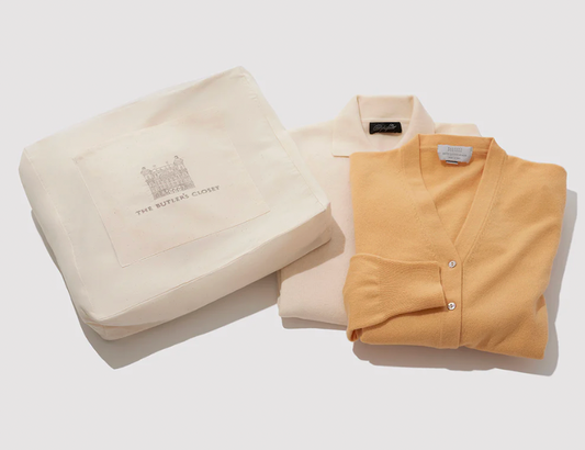 Folded cream and yellow knitwear beside branded fabric bag