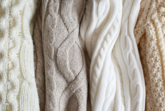 Folded cream, beige, and white cable knit cashmere sweaters