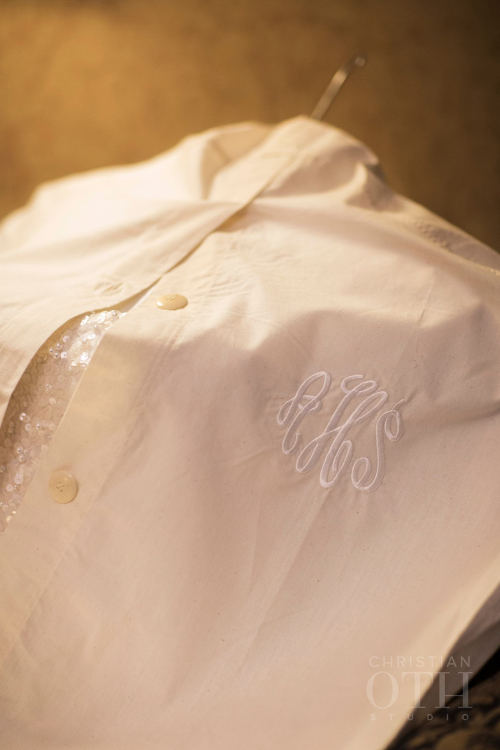 Monogrammed bridal garment cover with sequined dress partially visible