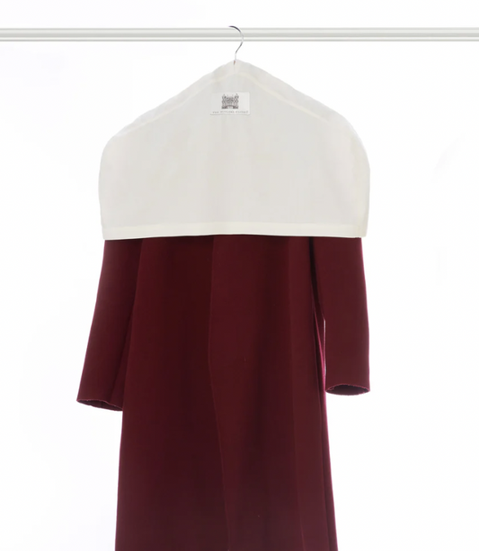 Red garment hanging on a hanger, covered with a white protective garment cover