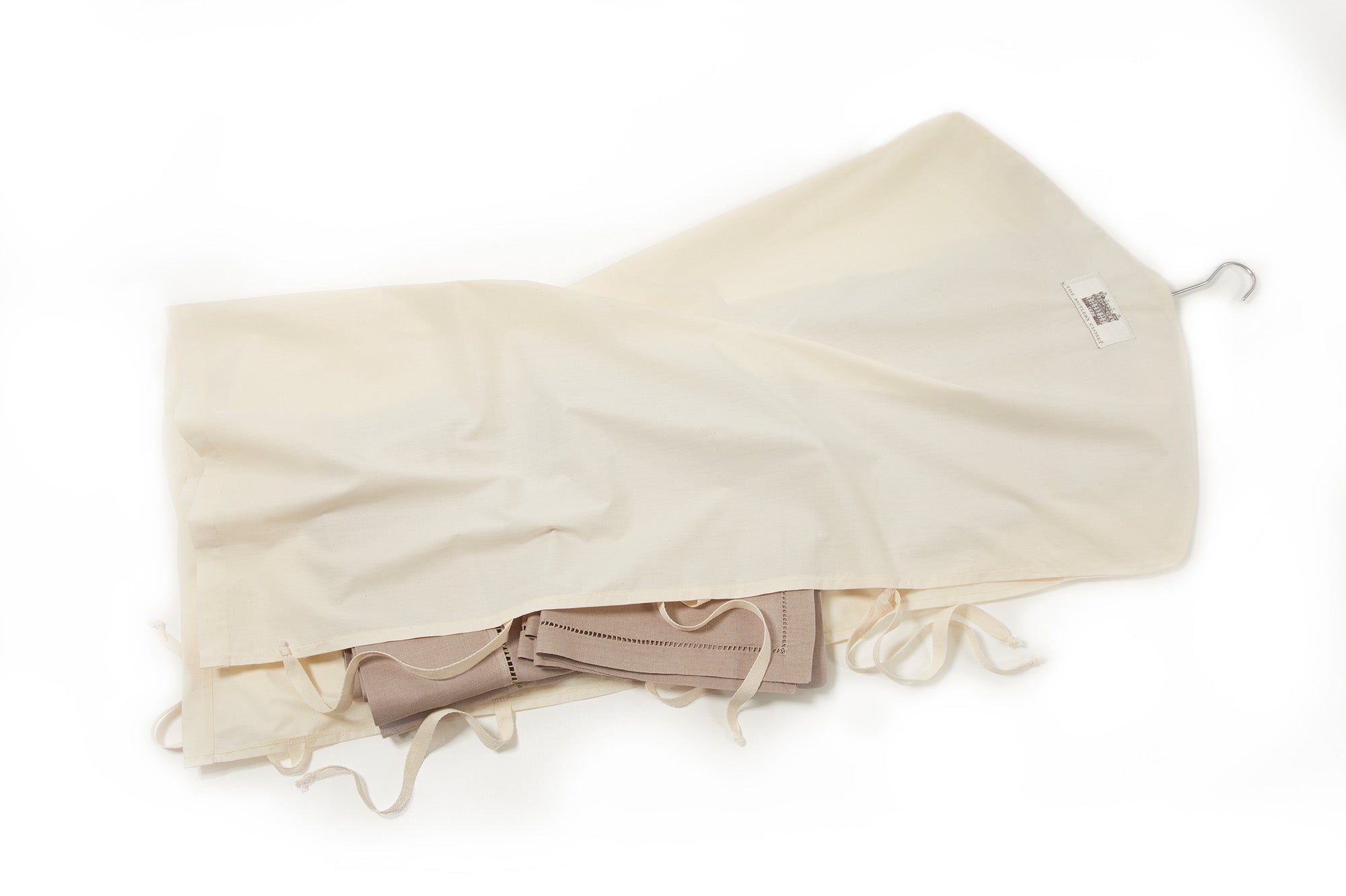 A cream-colored garment bag partially open, revealing a folded beige corset with laces inside.