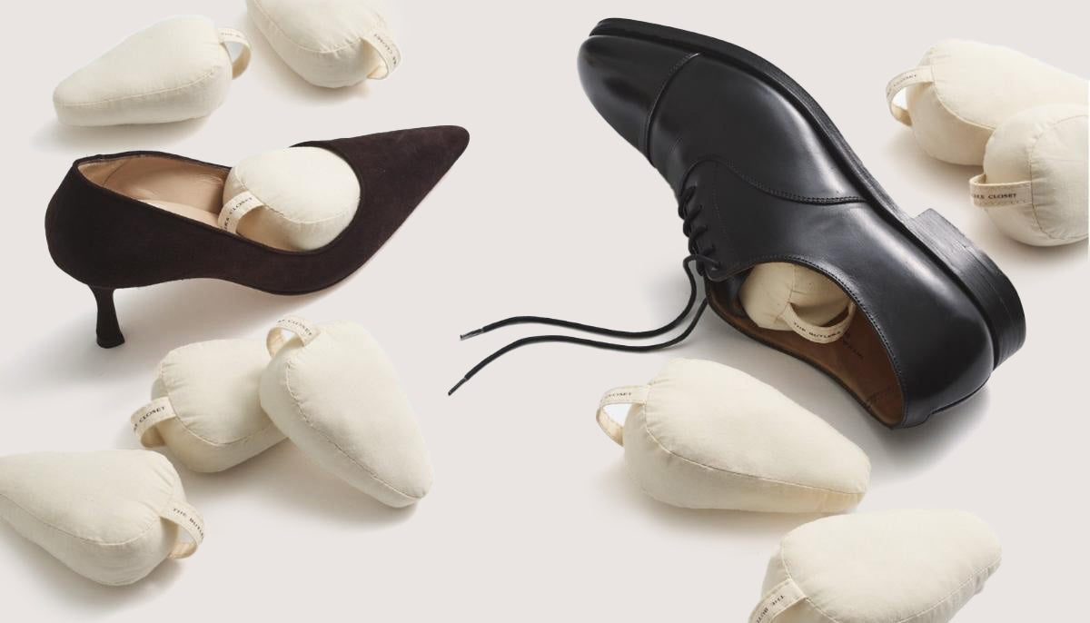 A black high-heeled shoe and a black oxford shoe both contain cushioned shoe shapers. Additional shoe shapers are scattered around.