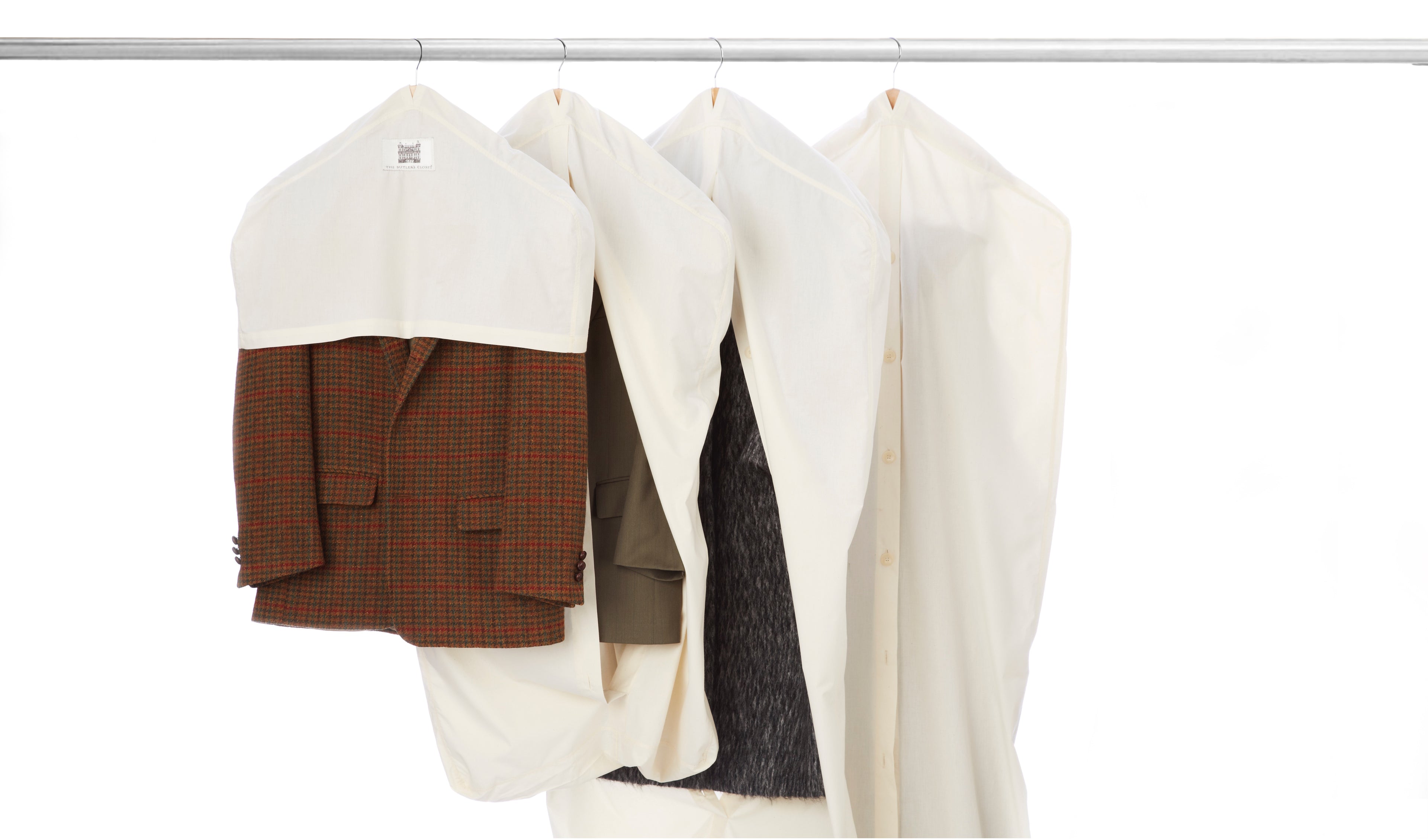 Four suits in garment bags hang on a clothing rack against a white background.