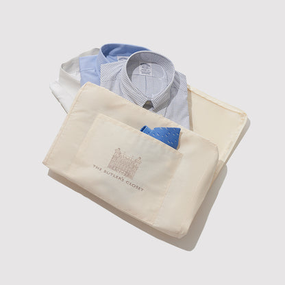 A Cotton Garment Bag With Three Folded Shirts Sticking Out The Top Of It