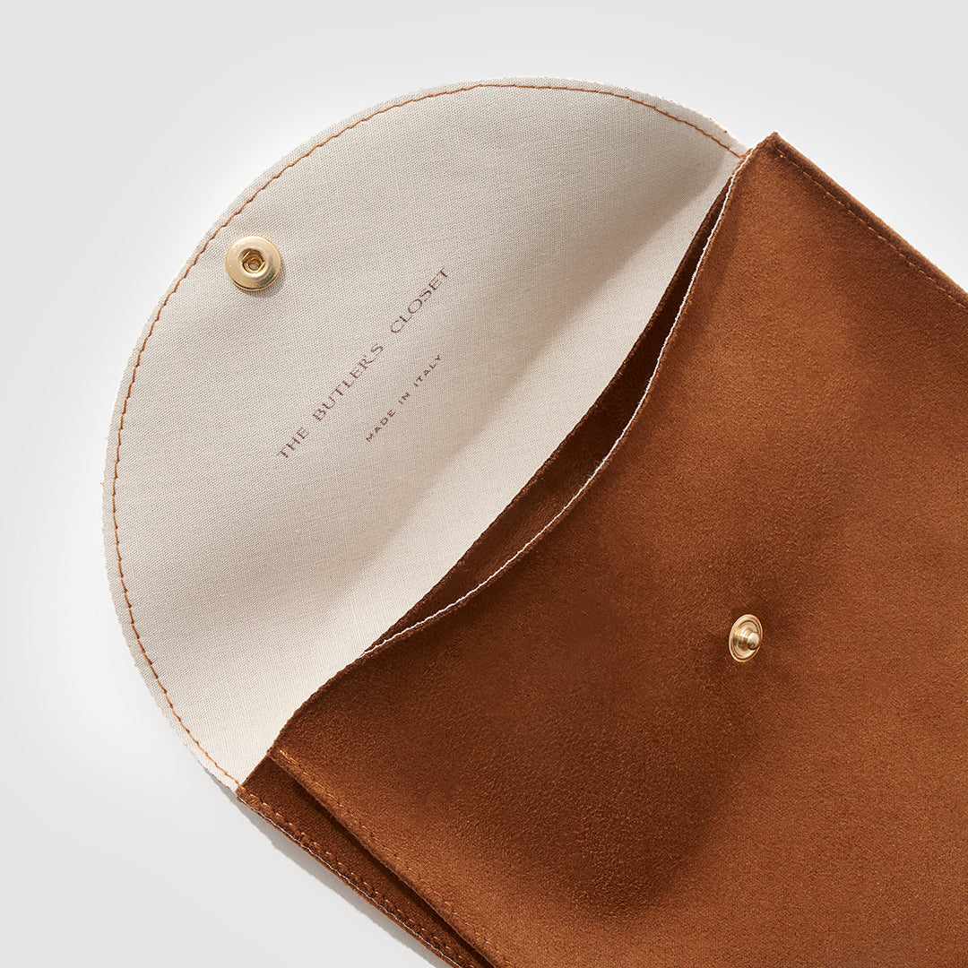 A Close Up Of An Open Brown Suede Jewelry Pouch