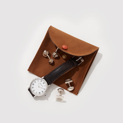 A Brown Suede Jewelry Pouch With A Watch And Some Cufflinks On Top Of It